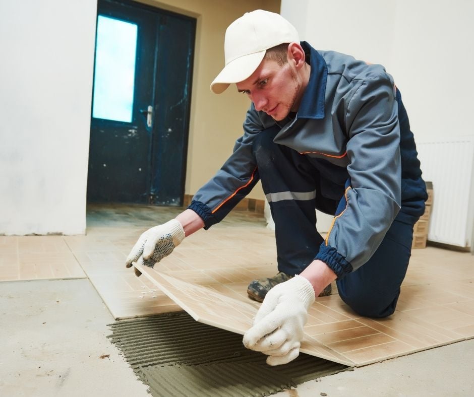 Man placing fresh, new tile in an unspecified room