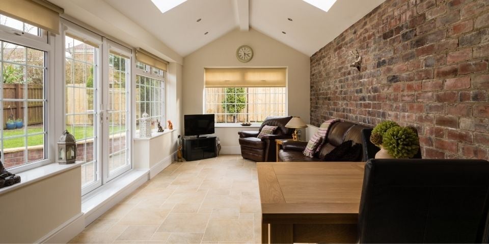 A Sunroom Featuring a Brick Wall and Brown Leather Furniture