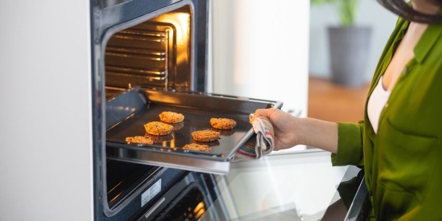 woman loading cookies into convection oven