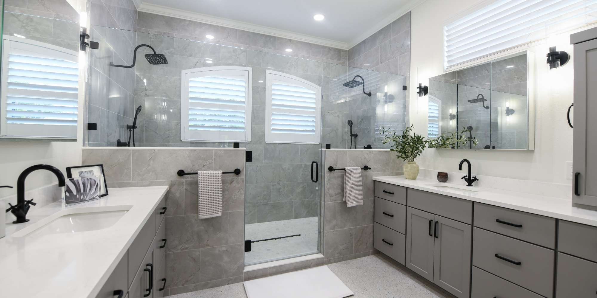 Bathroom remodel by Gilbert Design Build with double vanity, large glass shower, and modern gray cabinetry