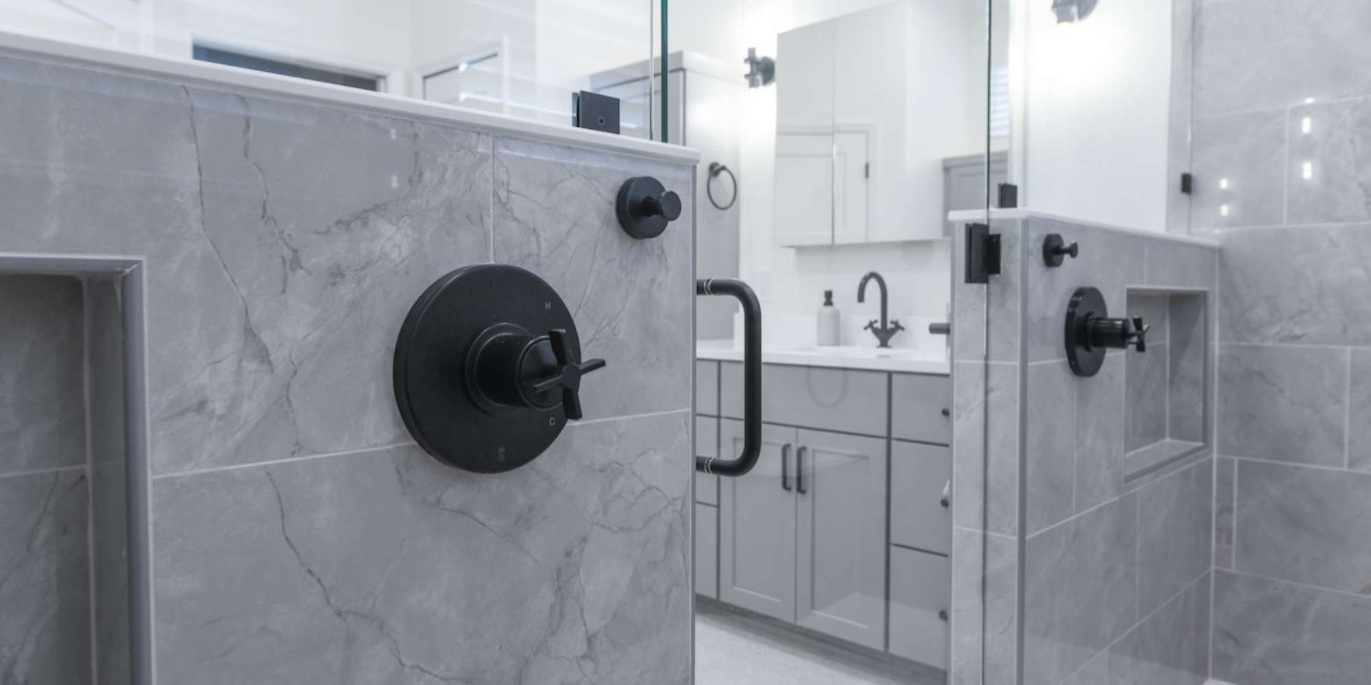 Contemporary bathroom remodel in Sarasota highlighting gray stone tile, custom niches, and bold black accents