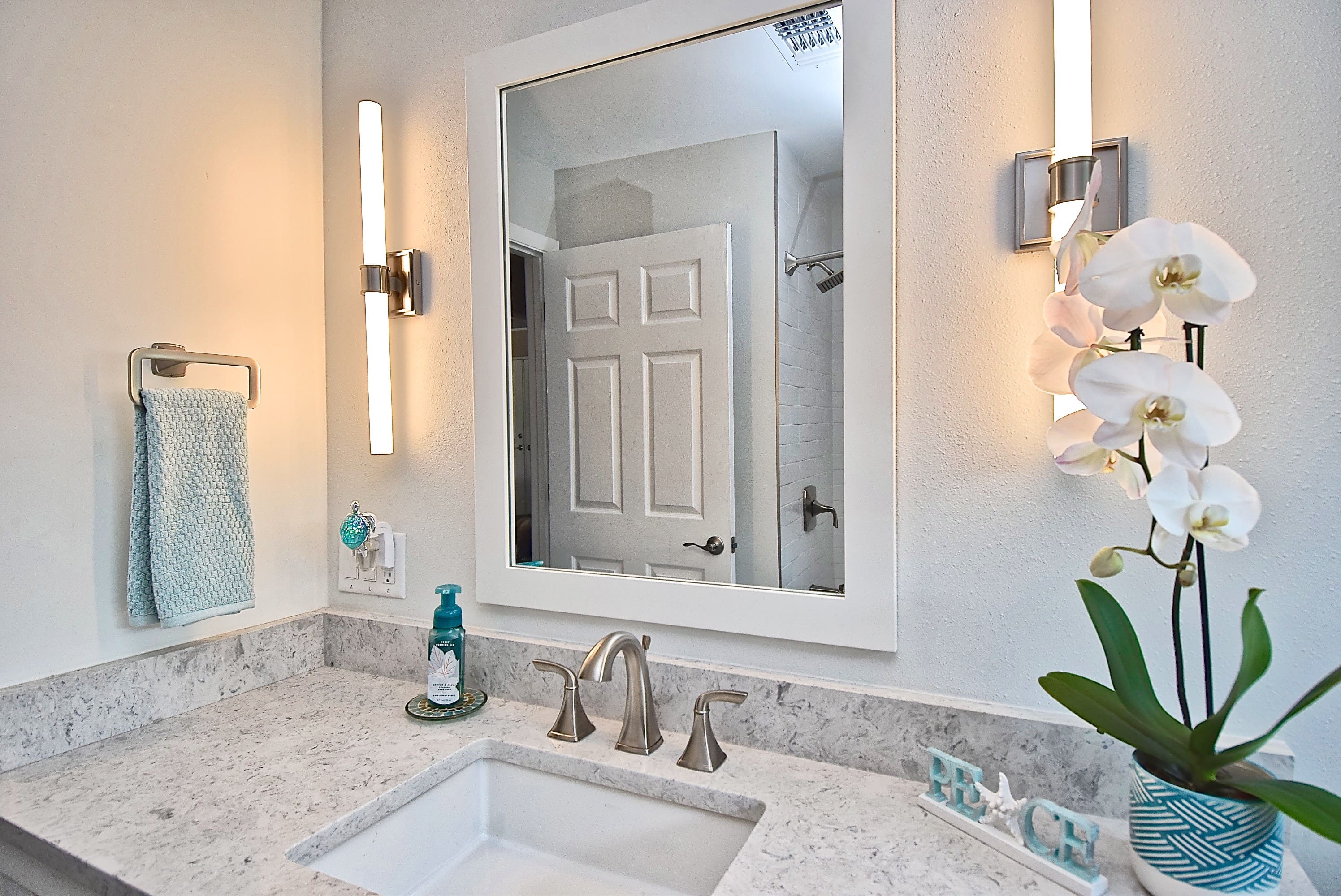 Remodeled Bathroom in Sarasota with White Marbled Countertops and Bar Sconce Lighting